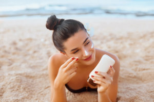 woman on the beach putting on sunscreen