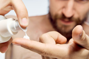 man putting skin cream on finger